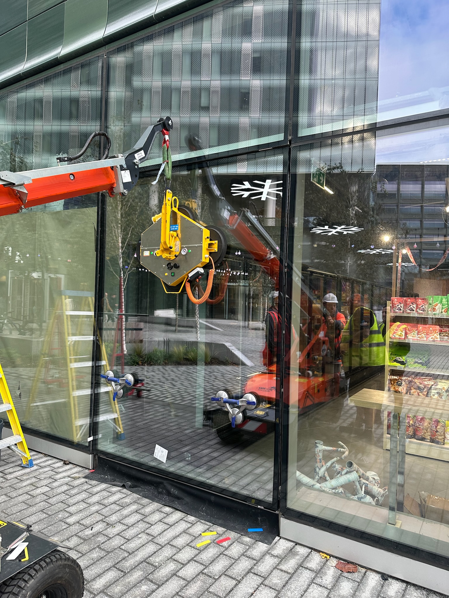 Glazing team lifting a replacement glass panel inside a shopping centre